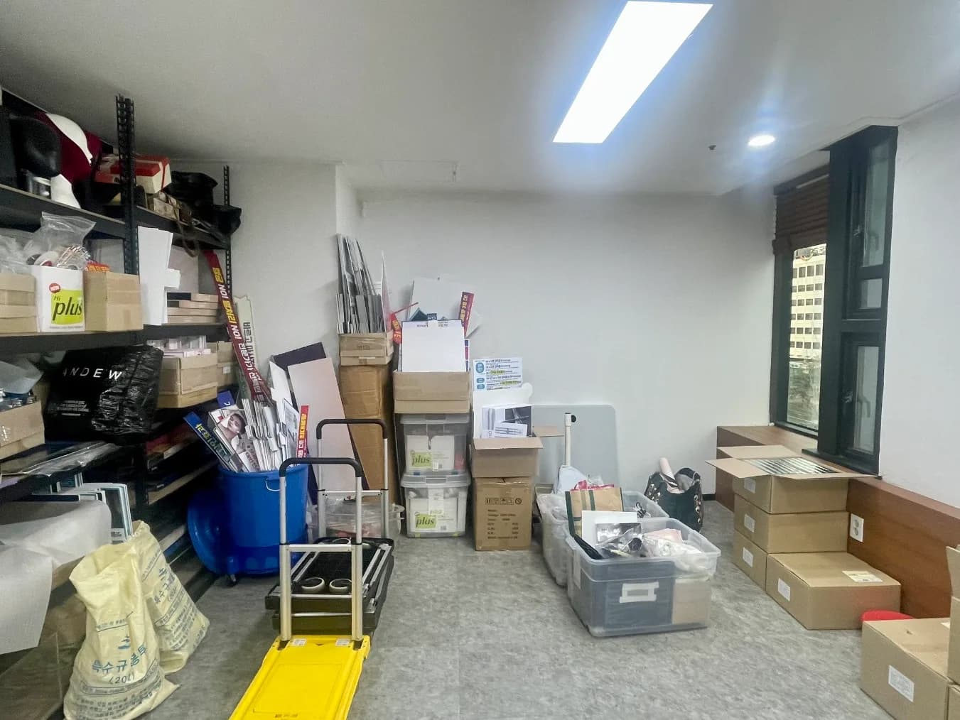 정리 전 창고 방. 상자와 통이 바닥에 쌓여 있다